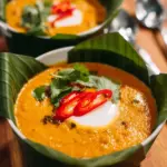 A vibrant dish of Thai steamed red curry (haw mok) served in a banana leaf.